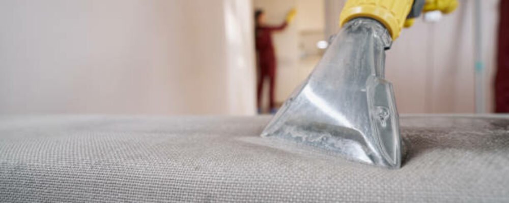 Cropped photo of skilled worker in rubber glove vacuuming sofa using stainless steel extractor nozzle